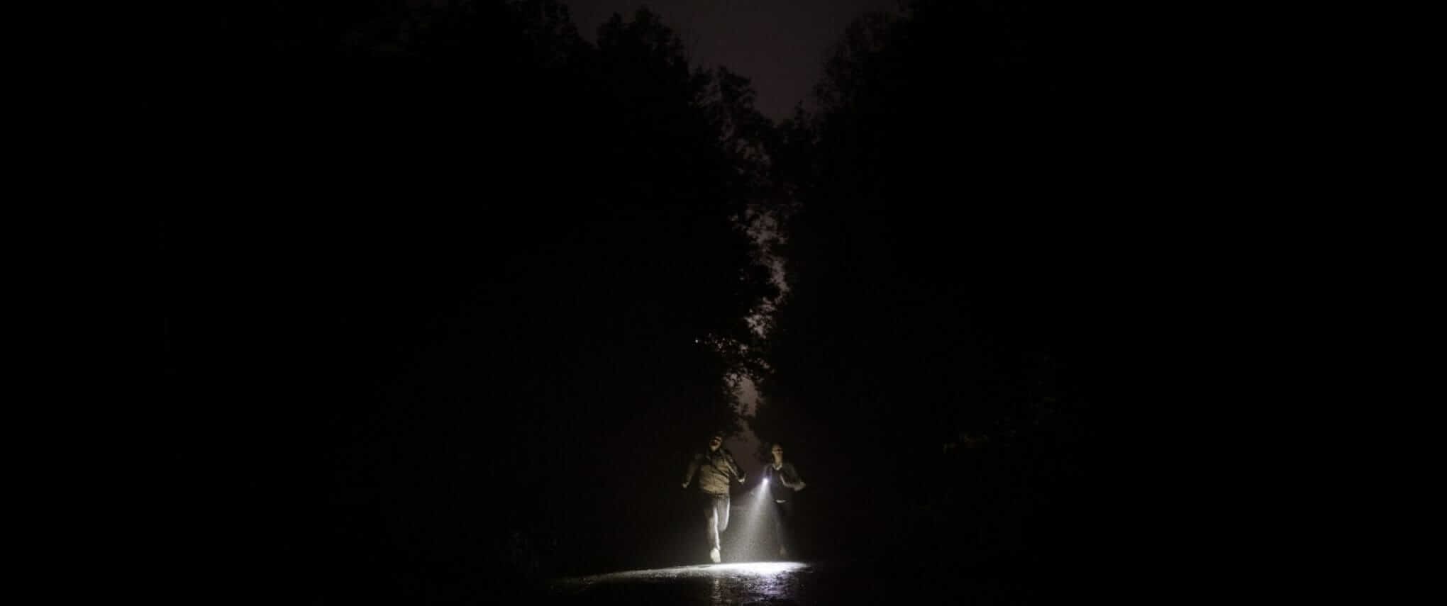 A still from The Toll, featuring Cami and Spencer running in pitch darkness