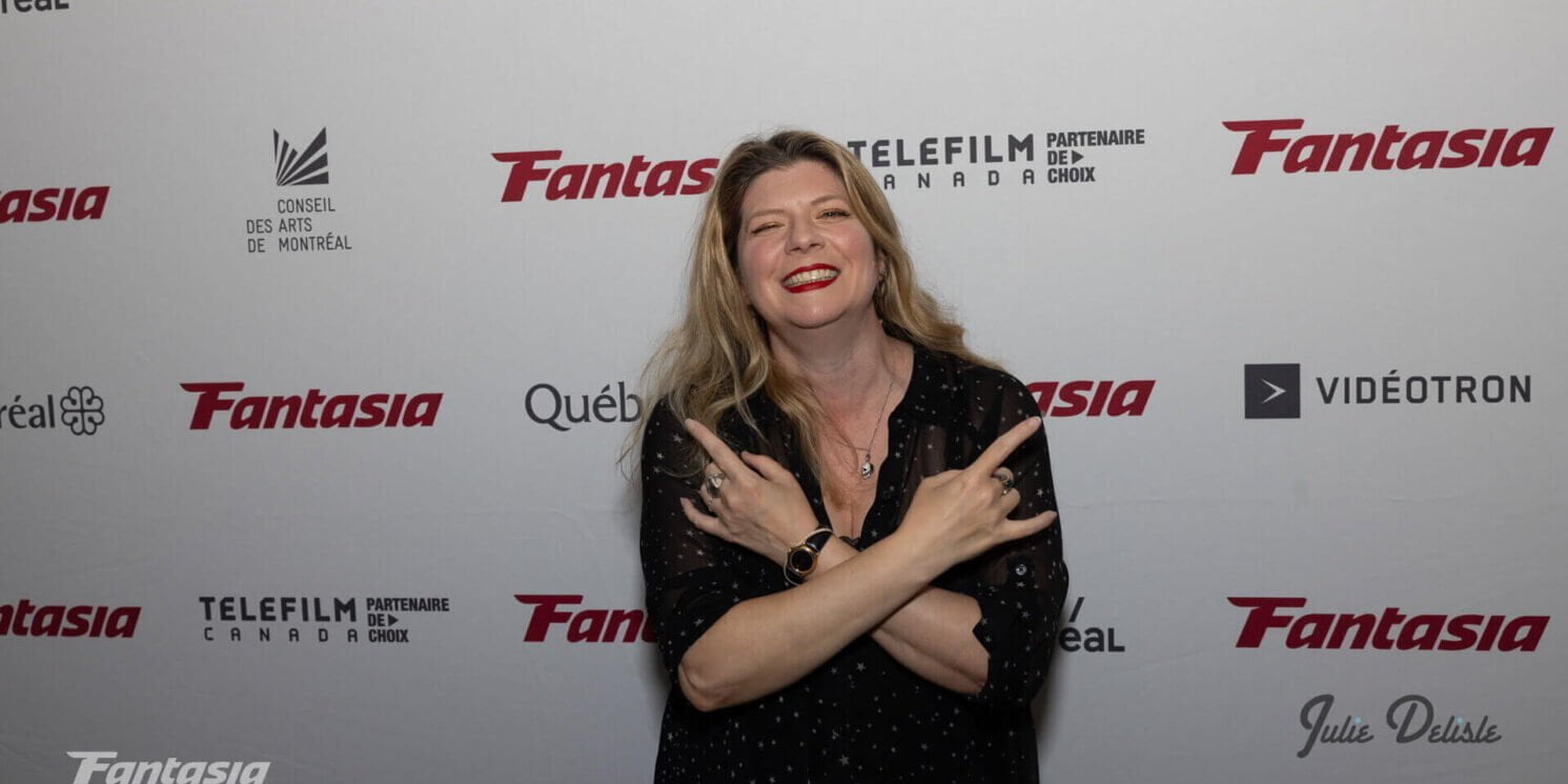 Izzy Lee at the Fantasia Film Festival Red Carpet giving the devil horns with both hands