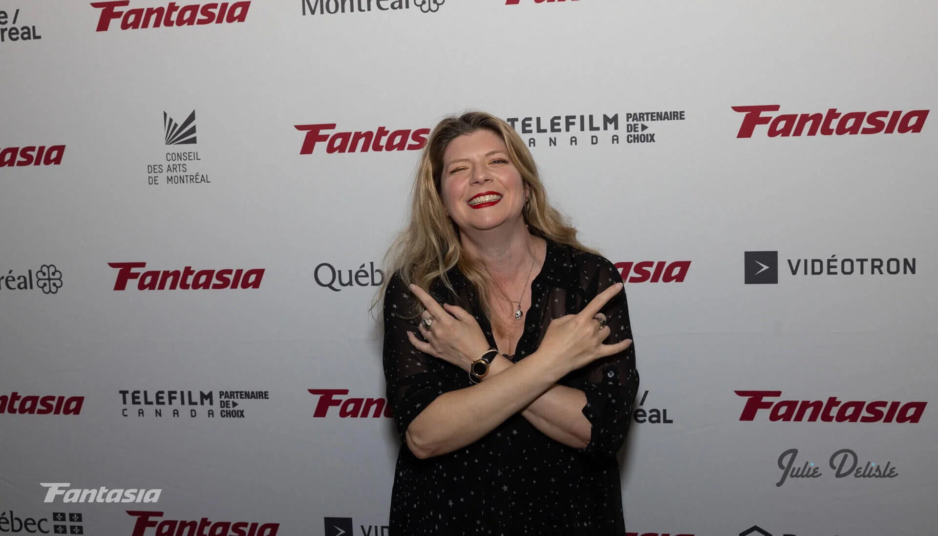 Izzy Lee at the Fantasia Film Festival Red Carpet giving the devil horns with both hands
