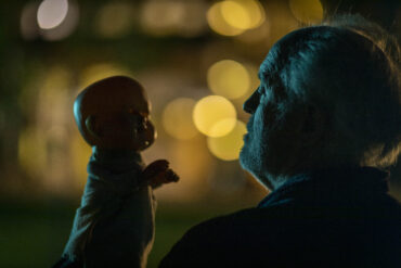 THE RULE OF JENNY PEN (2025) - John Lithgow as Dave Crealy talks with his hand Puppet Jenny Pen in the moonlight