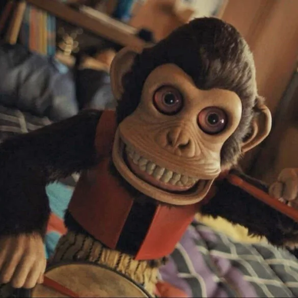 The Monkey (2025) - The Monkey Doll Bangs on His Drum with his creepy eyes wide open, baring his porcelain teeth