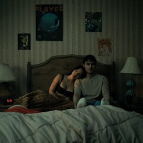 Inde Navarrette stars as Nikki and Michael Johnston as Bear in OBSESSION, a Focus Features release. Nikki and Bear Sitting next to each other in Bed